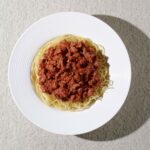 Top-down view of plant-based spaghetti Bolognese with vegan meat sauce on a white plate – Amoria Foods