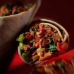Close-up of a sliced plant-based wrap filled with vegan beef, fresh vegetables, and creamy sauce – Amoria Foods